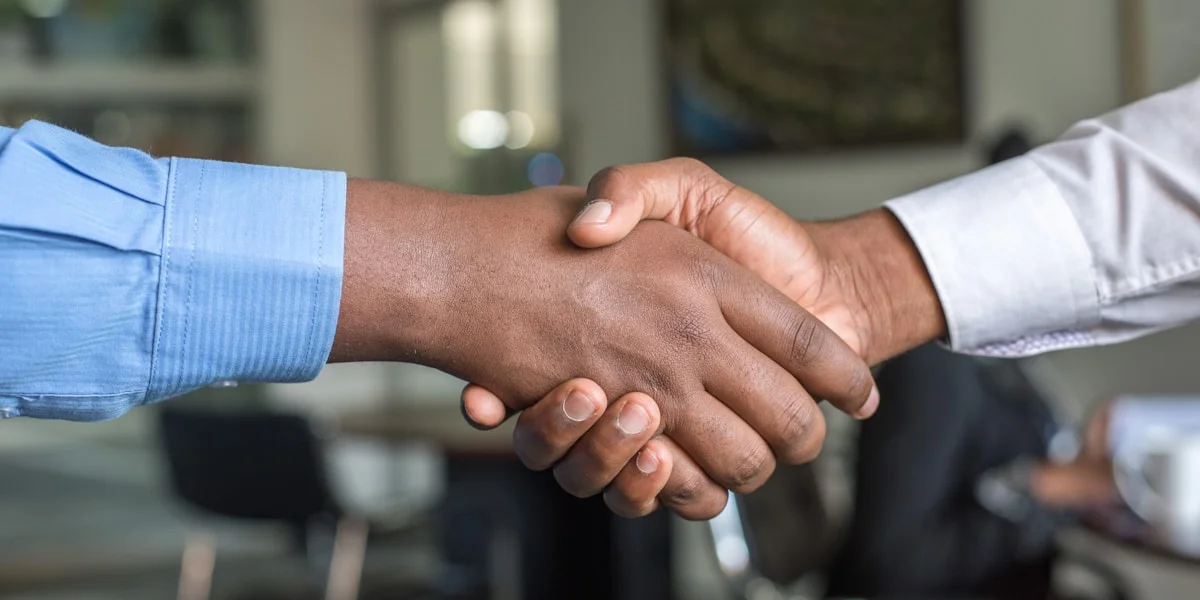 Two professionals shaking hands in a business setting representing trust and neutral partnership