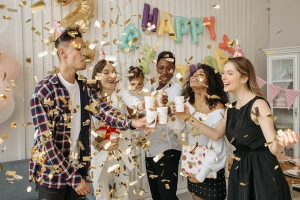 Friends celebrating a birthday with confetti and drinks